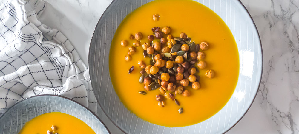 To skåle med orange hokkaidosuppe og ristede kikærter og græskarkerner på toppen